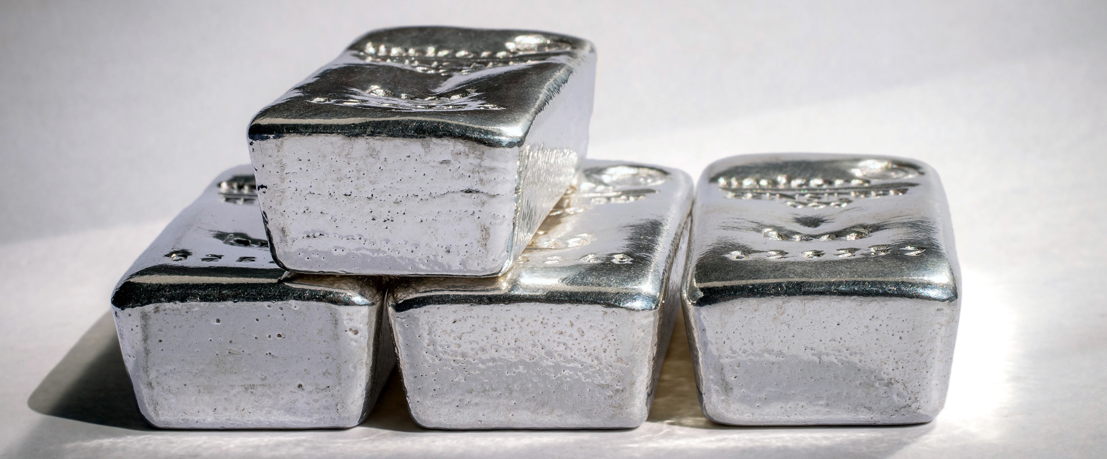 Die ideale Edelmetallinvestition. Silber-, Platin- und Palladiumbarren liegen auf einem weißen Untergrund.