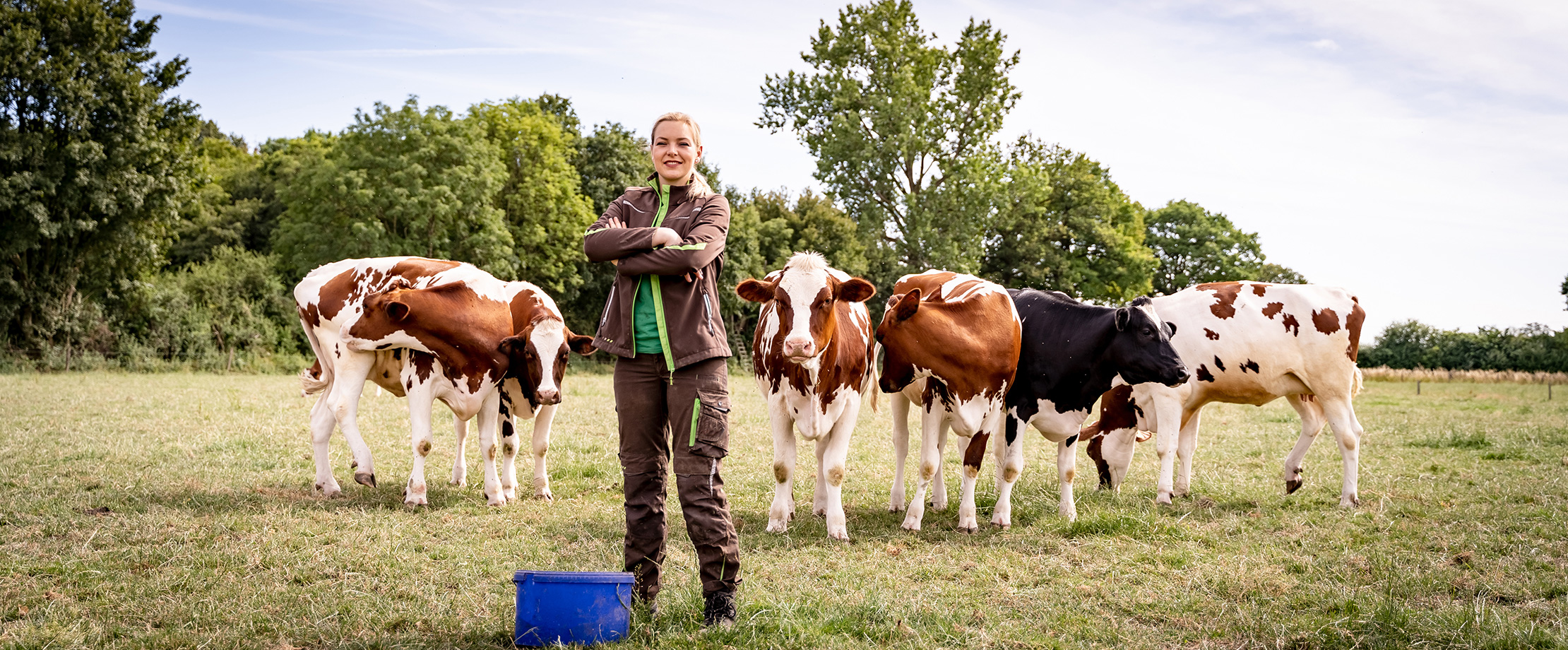 Die beste Landwirtschaftsversicherung Frau in Arbeitskleidung auf der Weide bei einigen Kühen.